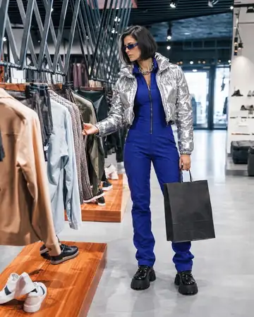 Nara Órbita eligiendo ropa en una tienda, con una bolsa en la mano